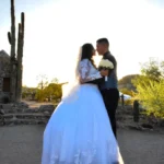 Pareja de novios posando en el desierto de Arizona durante la hora dorada para fotografía de bodas profesional.